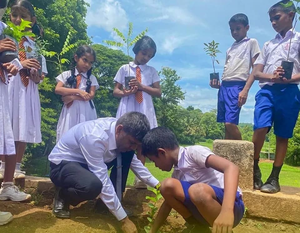 A teacher and students planting a sapling