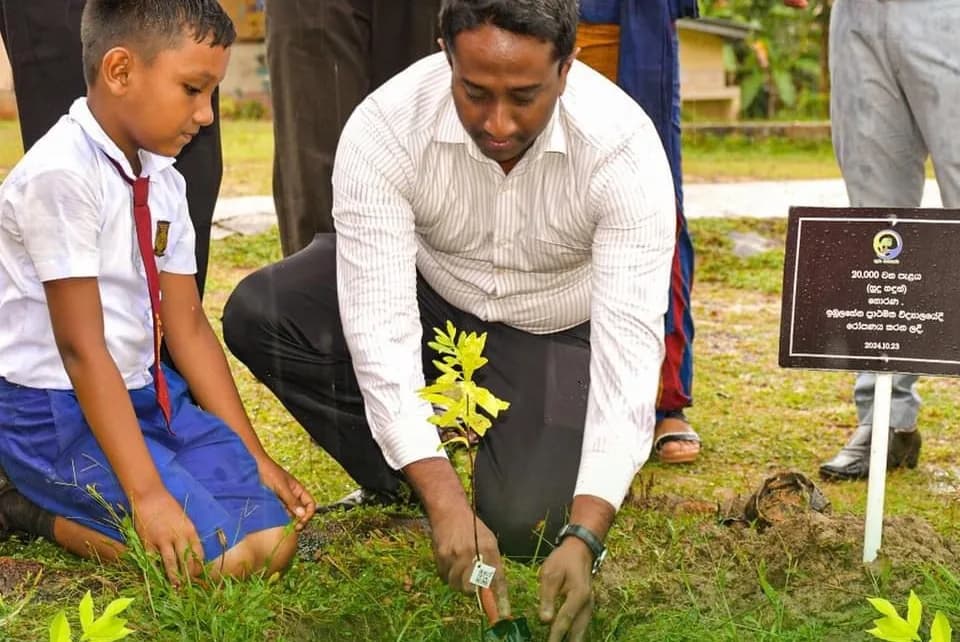 A teacher planting a sapling with a student
