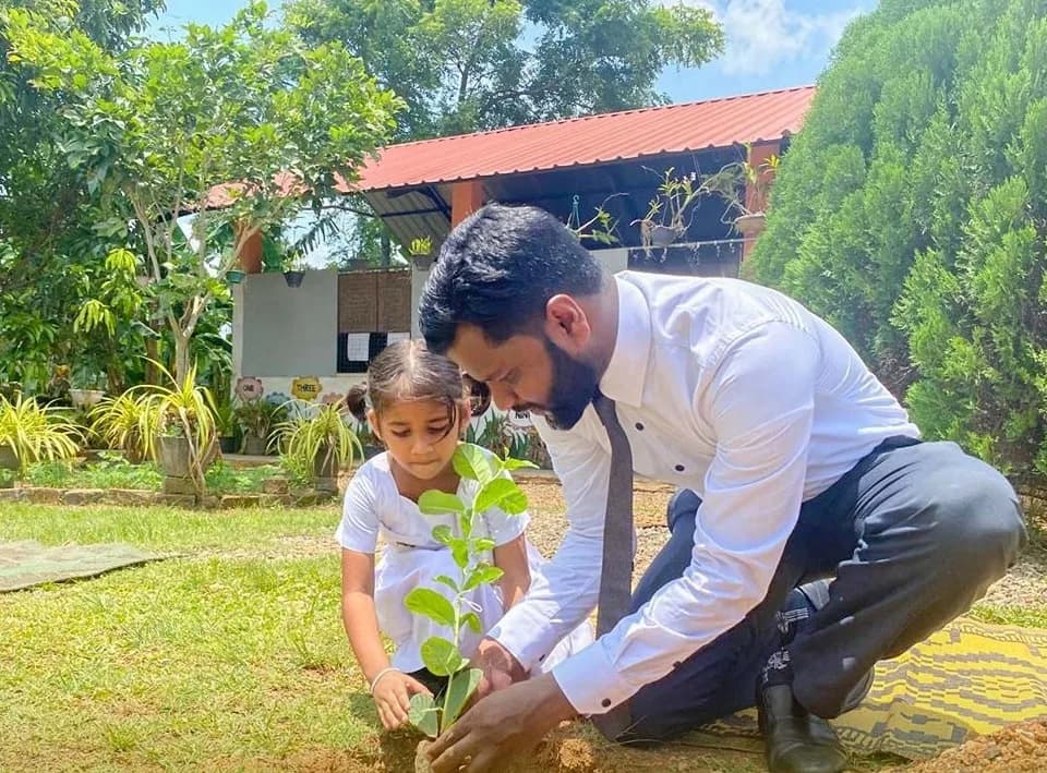 A parent and child planting a sapling